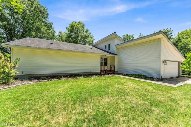 rear view of house with a garage and a yard