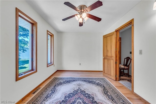 empty room with light wood-type flooring, ceiling fan, and a wealth of natural light