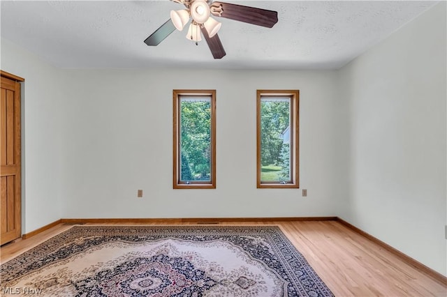 empty room featuring a textured ceiling, ceiling fan, and light hardwood / wood-style flooring