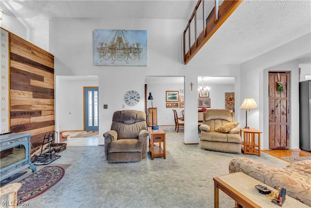 living room featuring carpet floors, a wood stove, a high ceiling, and a chandelier