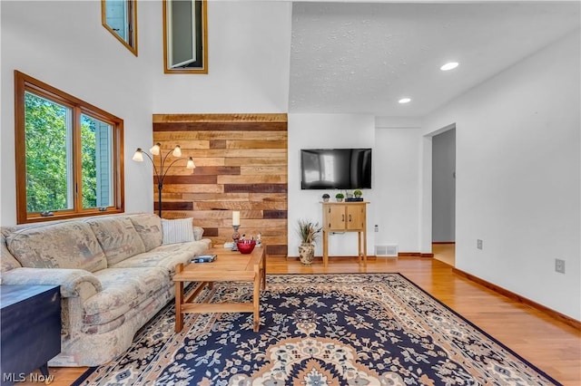 living room featuring hardwood / wood-style flooring, wooden walls, and a textured ceiling