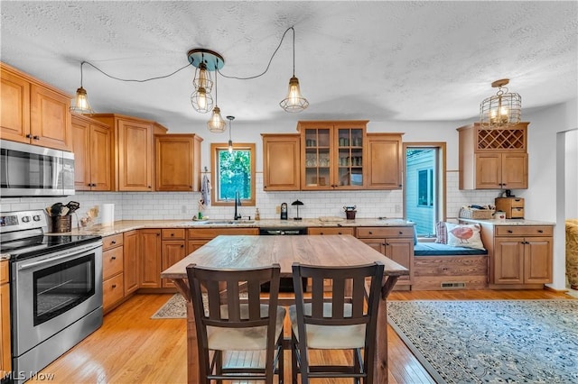 kitchen featuring sink, appliances with stainless steel finishes, a kitchen bar, and decorative light fixtures