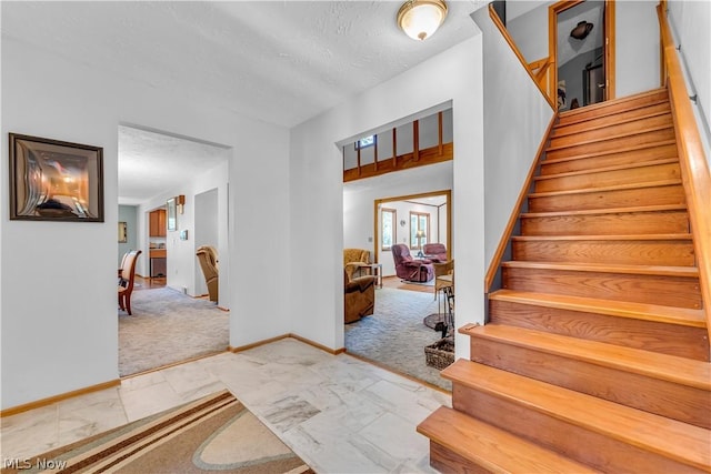 stairway with carpet flooring and a textured ceiling