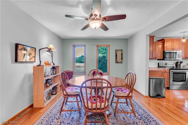 dining room featuring light hardwood / wood-style floors, ceiling fan, and a textured ceiling