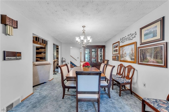 carpeted dining room with a notable chandelier and a textured ceiling