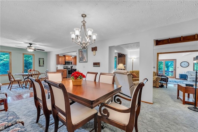 dining area featuring ceiling fan with notable chandelier, light wood-type flooring, and a textured ceiling