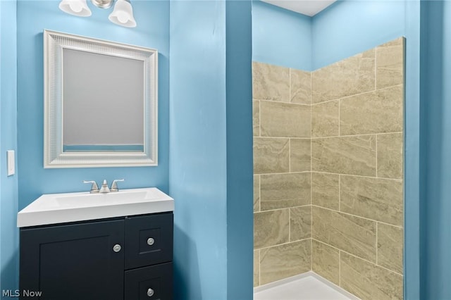 bathroom featuring a tile shower and vanity