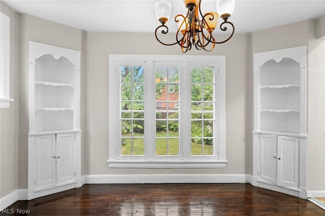 unfurnished dining area with dark hardwood / wood-style flooring and an inviting chandelier