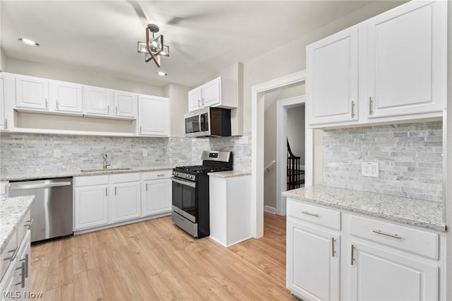 kitchen with stainless steel appliances, white cabinetry, sink, and tasteful backsplash