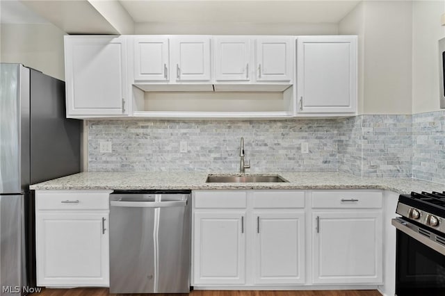 kitchen featuring light stone counters, decorative backsplash, white cabinets, appliances with stainless steel finishes, and sink