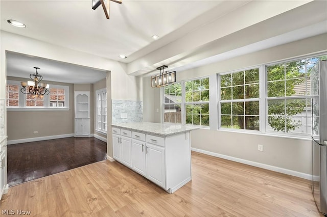 kitchen featuring a chandelier, light stone counters, decorative backsplash, white cabinetry, and decorative light fixtures