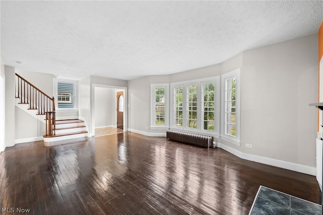 unfurnished living room featuring radiator, wood-type flooring, and a textured ceiling