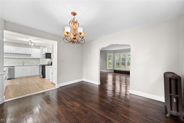 unfurnished dining area with sink, hardwood / wood-style floors, radiator heating unit, and a chandelier