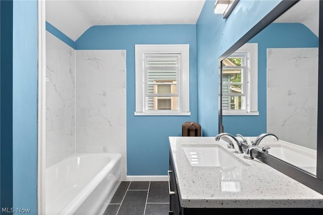 bathroom featuring a bath, vanity, lofted ceiling, and tile patterned floors