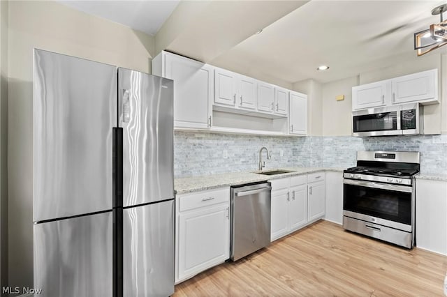 kitchen with appliances with stainless steel finishes, white cabinetry, decorative backsplash, and sink