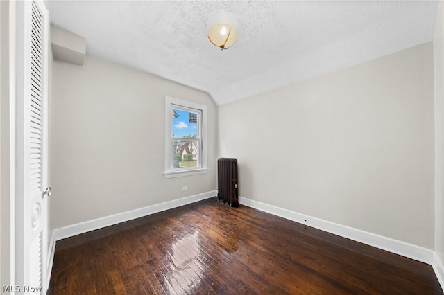 unfurnished bedroom with lofted ceiling, a textured ceiling, radiator heating unit, and dark hardwood / wood-style floors