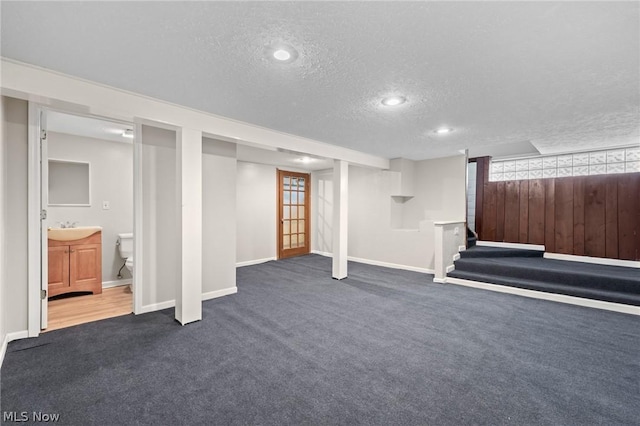 basement featuring a textured ceiling, carpet floors, and sink