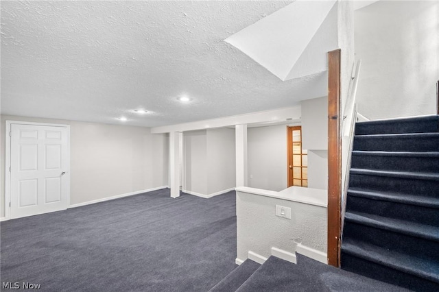 basement with a textured ceiling and dark carpet