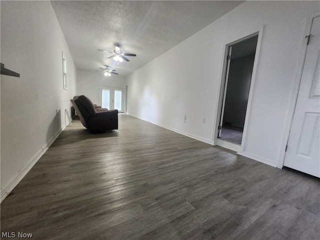 unfurnished living room featuring french doors, ceiling fan, dark hardwood / wood-style flooring, and a textured ceiling