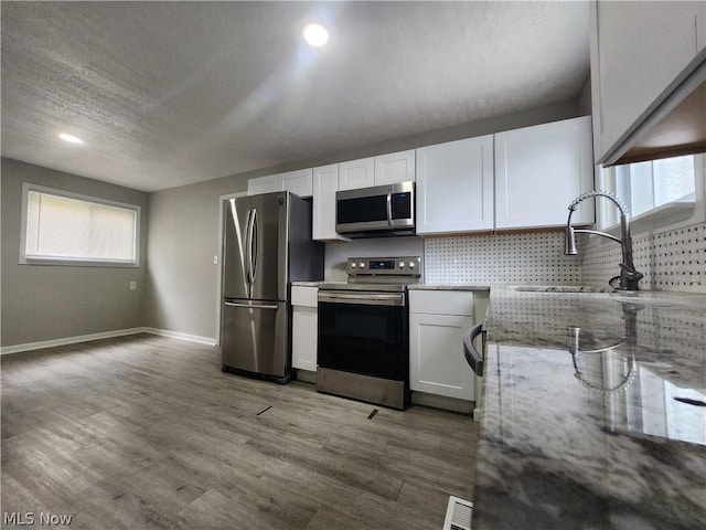 kitchen featuring white cabinets, sink, a textured ceiling, appliances with stainless steel finishes, and light stone counters