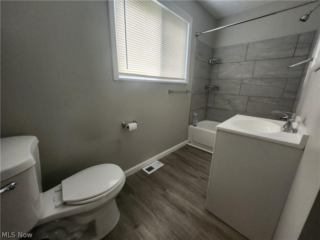 full bathroom featuring hardwood / wood-style flooring, tiled shower / bath combo, toilet, and vanity