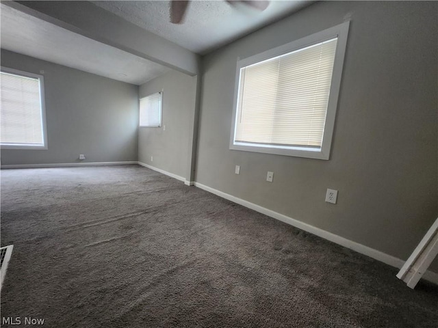 empty room featuring ceiling fan, dark carpet, and a textured ceiling