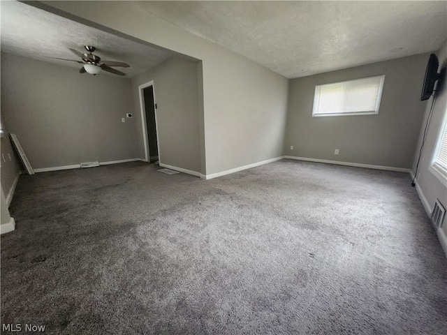 unfurnished room featuring ceiling fan, dark carpet, and a textured ceiling