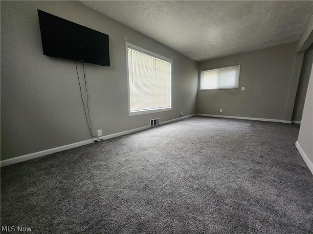 empty room featuring dark colored carpet and a textured ceiling