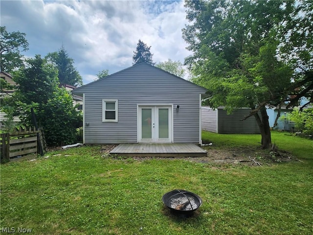 back of property with french doors, an outdoor fire pit, a lawn, and a wooden deck