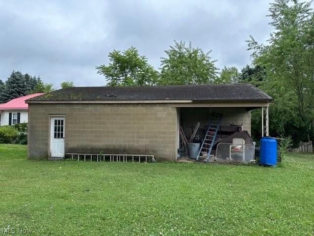 exterior space featuring an outbuilding, concrete block siding, and a lawn