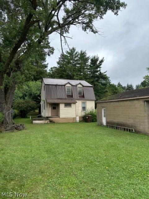 rear view of house with metal roof, a yard, and a gambrel roof