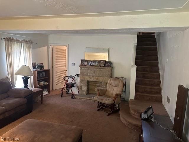 living room with carpet, stairs, and a stone fireplace