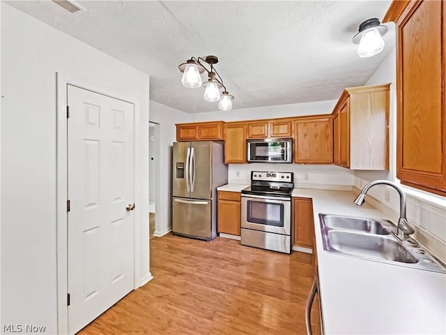 kitchen with sink, light hardwood / wood-style flooring, a textured ceiling, and stainless steel appliances