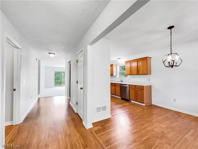 hall with light hardwood / wood-style floors, a textured ceiling, and a wealth of natural light