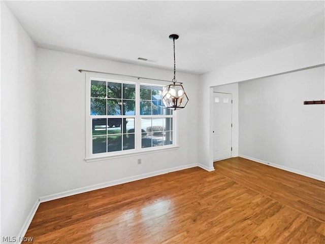 unfurnished dining area with hardwood / wood-style flooring and a chandelier