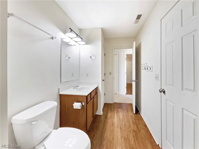 bathroom with hardwood / wood-style flooring, toilet, and vanity