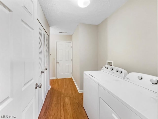 laundry room with a textured ceiling, light hardwood / wood-style flooring, and washing machine and dryer