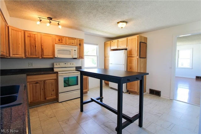 kitchen with a textured ceiling, white appliances, and sink