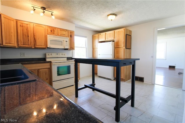 kitchen with a textured ceiling, sink, and white appliances