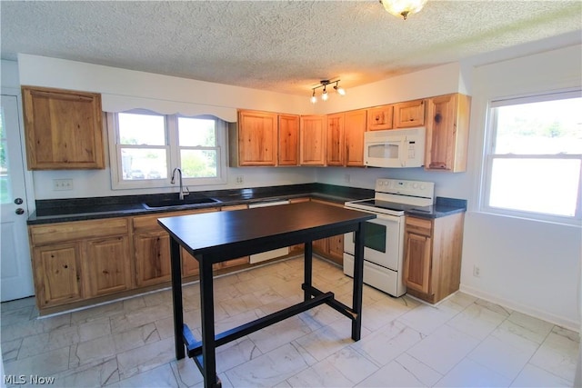 kitchen with a textured ceiling, white appliances, and sink