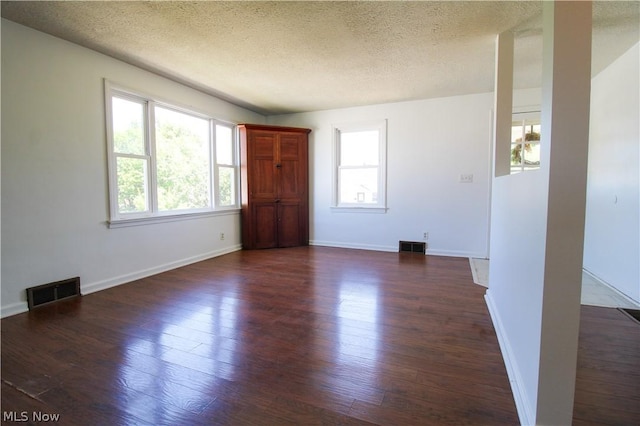 unfurnished room with a textured ceiling and dark wood-type flooring