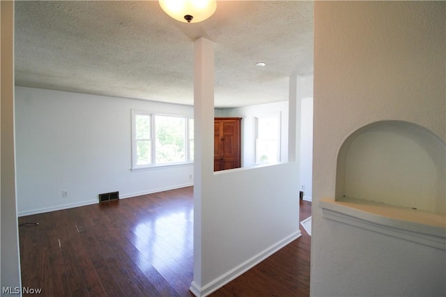 hallway with a textured ceiling and dark hardwood / wood-style flooring