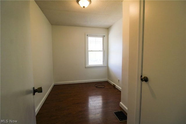 empty room featuring a textured ceiling and dark hardwood / wood-style floors