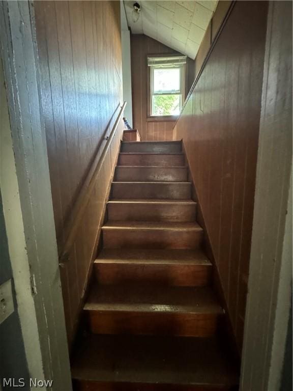 stairs with wooden walls and vaulted ceiling