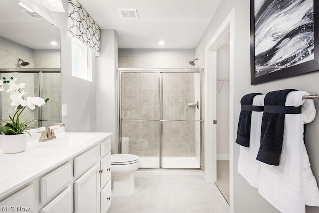 bathroom featuring tile patterned flooring, vanity, toilet, and walk in shower