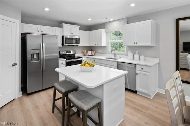 kitchen featuring a center island, sink, a kitchen bar, white cabinetry, and stainless steel appliances