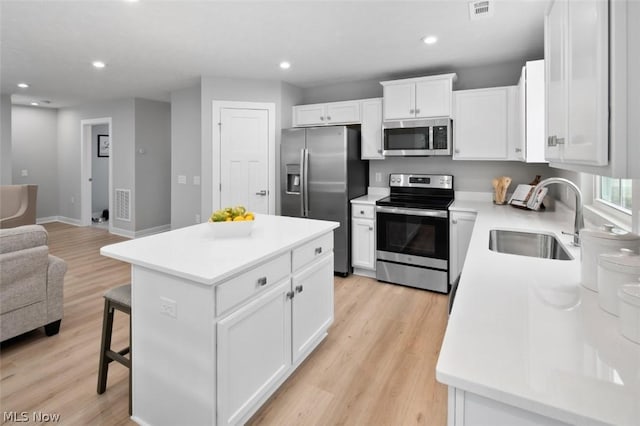 kitchen with white cabinets, a center island, sink, and stainless steel appliances