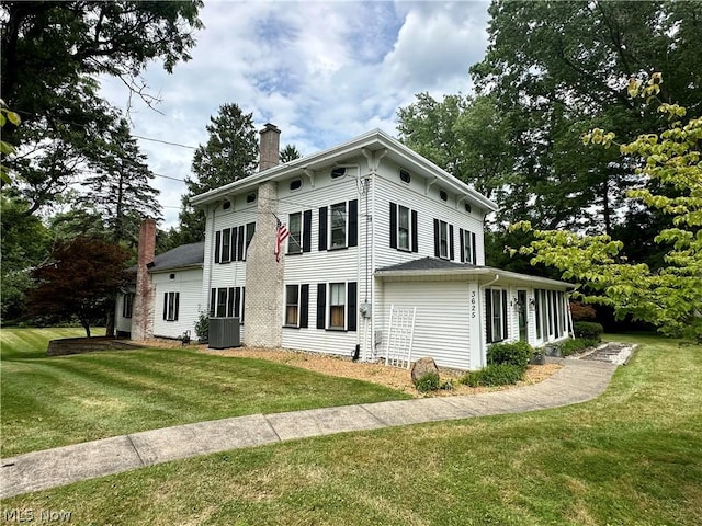 view of side of property with a lawn and central AC