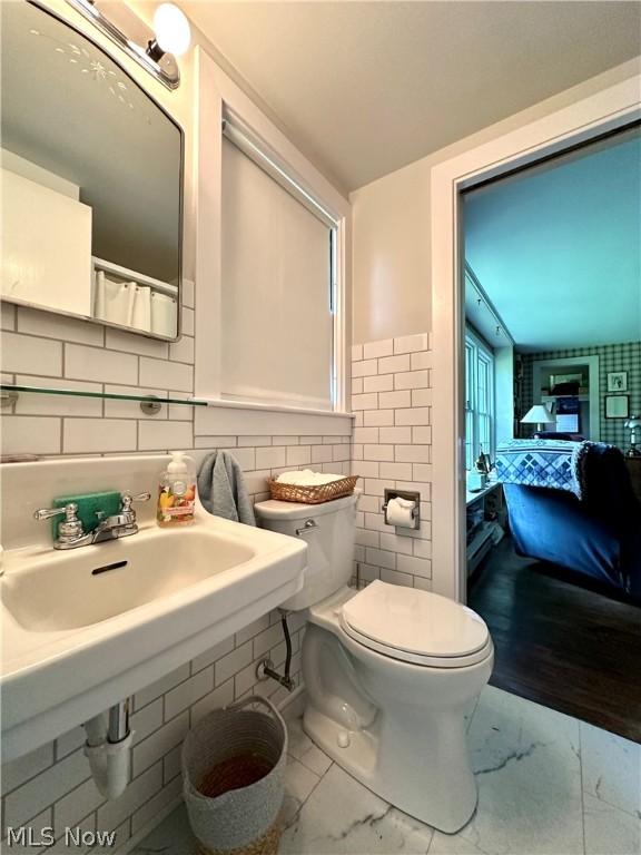 bathroom with toilet, tile walls, and sink