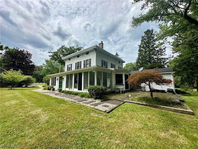 rear view of house featuring a lawn and a sunroom